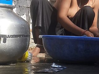 Indian stepsister is preparing to take a bath while washing clothes in the open courtyard of the house