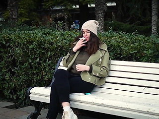 Young Brunette Is Taking an Unhurried Stroll with Allwhite 120mm Cigarette
