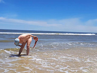 Amateur filming. A nudist plays with waves on the ocean shore.