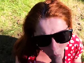 Kinky redhead with big tits gives a blowjob outdoors