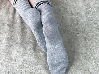 Girl in bed strokes her legs in gray cotton socks