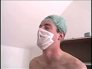 Girl in ponytails kneels to suck off a surgical masked doctor