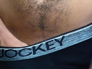Young man wearing black underwear is dancing cock while holding his groin area.