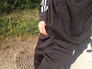 Freeballing public twink walks outdoors commando no underwear beneath black Adidas tracksuit Campus sneakers while out cruising